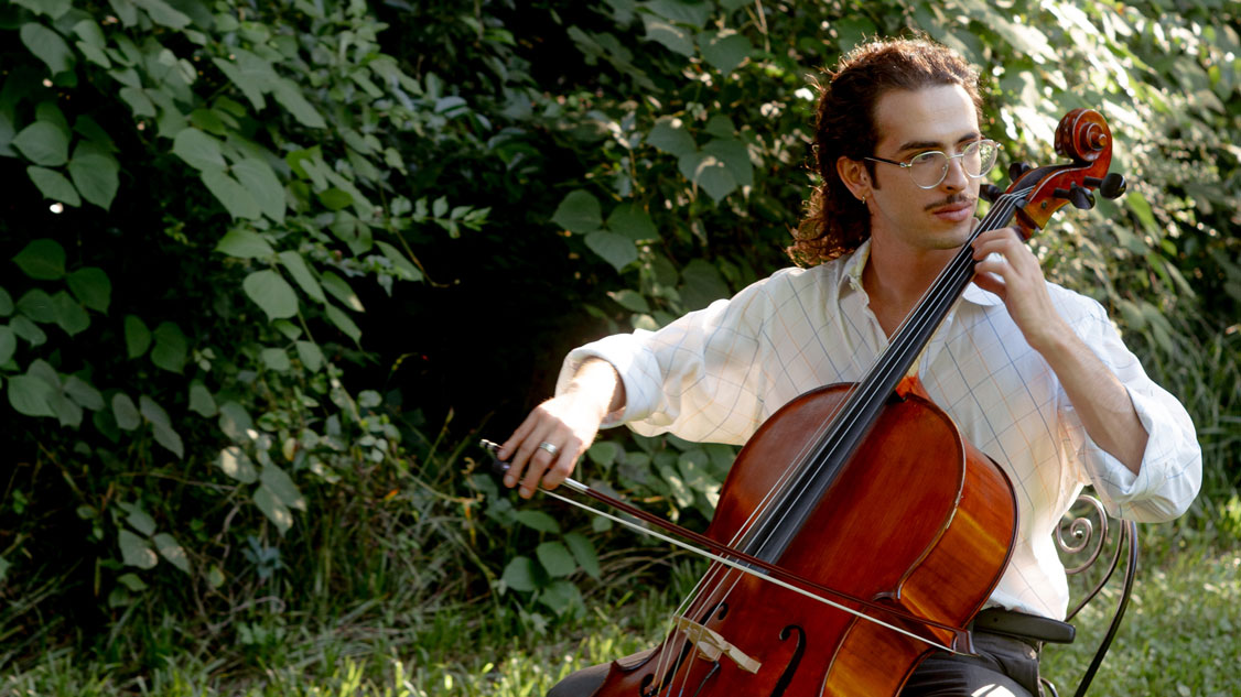 Jordi looks pensive playing his cello outside in nature.