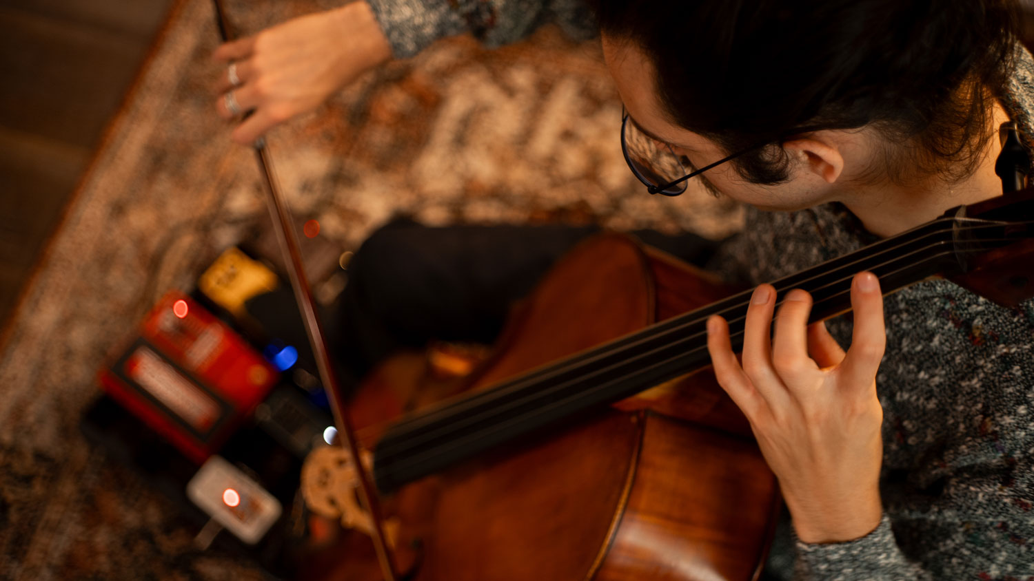 Top-down shot of Jordi experimenting with his cello and a footpedal.