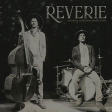 The members of Reverie posed alongside a bass and a drum kit.