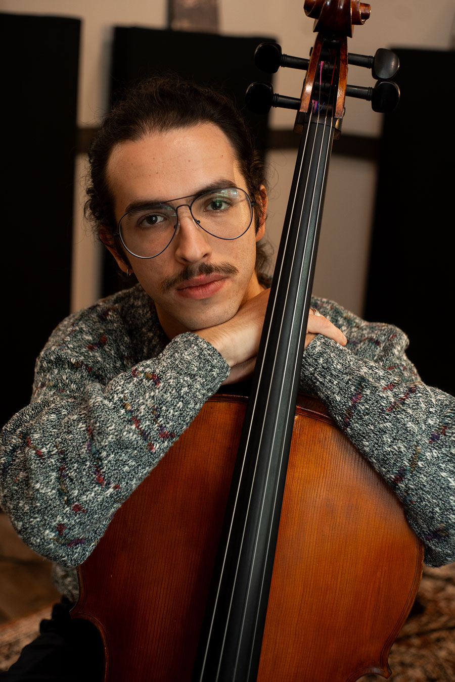 With his arms resting atop his cello, Jordi gives the camera a look of sincerity.