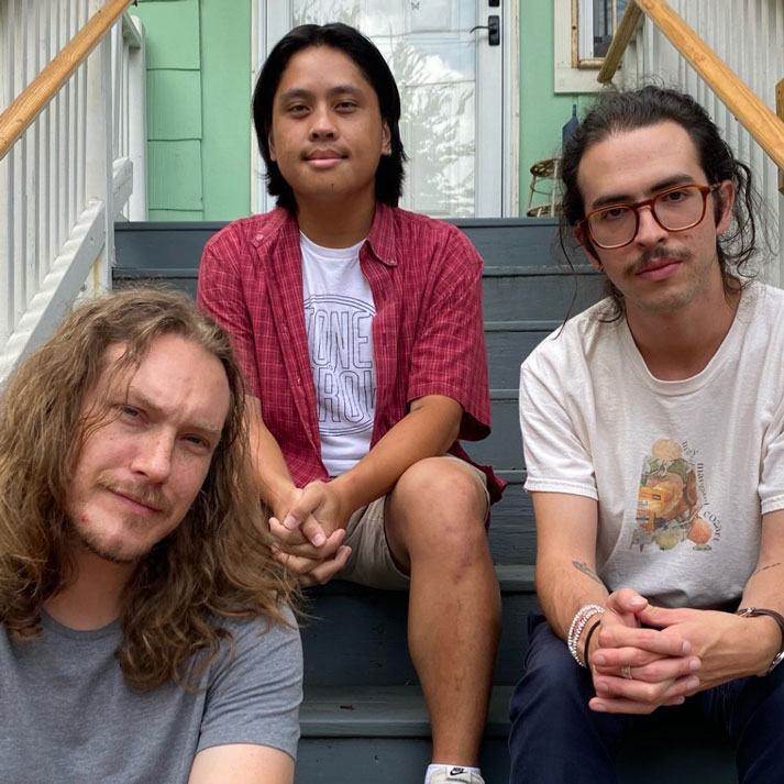 LSV Trio's three members sitting in a stairwell, softly smiling.