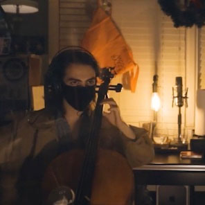 Jordi wearing a surgical mask playing the cello in someone's home office.